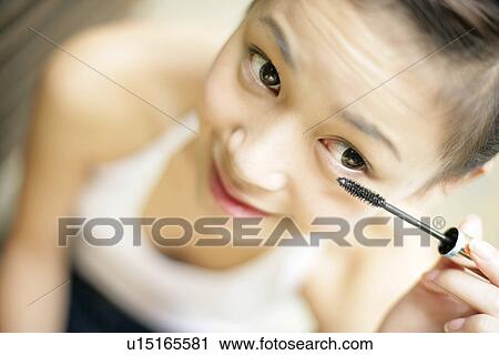 Stock Image - Elevated view of a young woman applying mascara.. Fotosearch