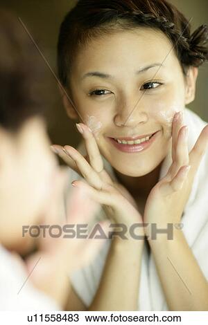 Mirror image of a young woman applying a cream. View Large Photo Image Stock Image - Mirror image of a young woman applying a cream.. Fotosearch