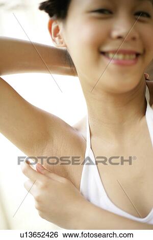 Portrait of a young woman spraying deodorant. View Large Photo Image Stock Photograph - Portrait of a young woman spraying deodorant.. Fotosearch