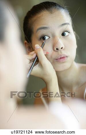 Picture - View of a young woman applying an eyebrow pencil.. Fotosearch