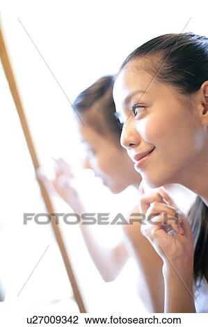 View of a young woman looking at mirror. View Large Photo Image Stock Image - View of a young woman looking at mirror.. Fotosearch