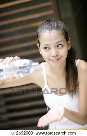 Stock Photo - View of a young woman pouring water on hands.. Fotosearch