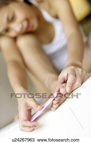 Stock Image - View of a young woman shaping nails.. Fotosearch