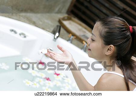 View of a young woman sitting beside a bathtub. View Large Photo Image Picture - View of a young woman sitting beside a bathtub.. Fotosearch