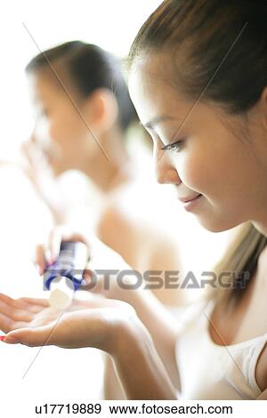 Stock Photo - View of a young woman squeezing a tube of cream.. Fotosearch