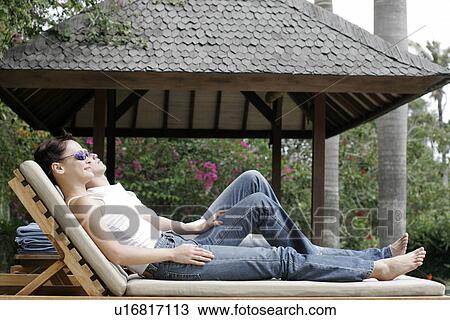Stock Image - Couple lying on a reclining chair.. Fotosearch