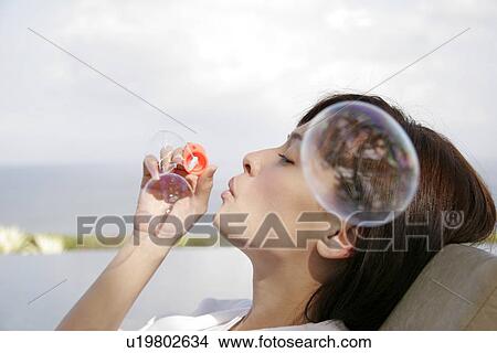 Profile of a young woman blowing bubbles. View Large Photo Image Picture - Profile of a young woman blowing bubbles.. Fotosearch
