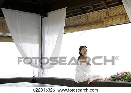 Rear view of a woman sitting on the edge. View Large Photo Image Stock Photography - Rear view of a woman sitting on the edge.. Fotosearch