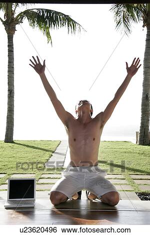 Stock Photograph - View of a man kneeling and hands raised.. Fotosearch