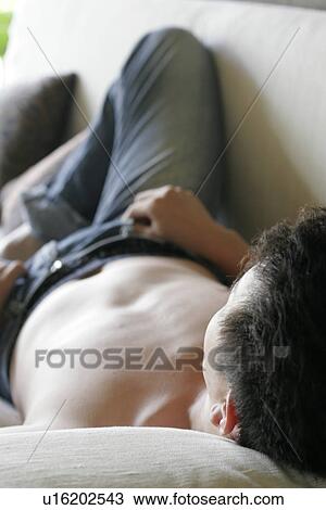 View of a man lying on a sofa. View Large Photo Image Stock Image - View of a man lying on a sofa.. Fotosearch