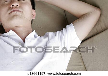 View of a man lying on a sofa. View Large Photo Image Stock Photo - View of a man lying on a sofa.. Fotosearch
