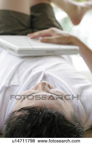 View of a man lying with a laptop. View Large Photo Image Stock Photo - View of a man lying with a laptop.. Fotosearch