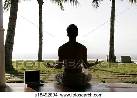 View of a man sitting besides a laptop. View Large Photo Image Picture - View of a man sitting besides a laptop.. Fotosearch