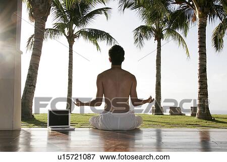 Stock Photo - View of a man sitting besides a laptop.. Fotosearch