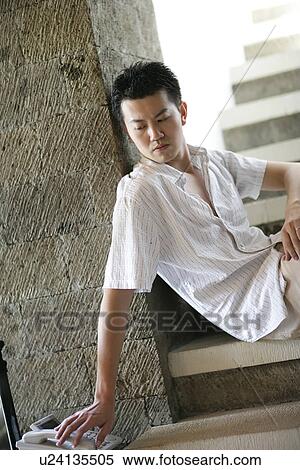 Stock Photography - View of a man sitting on staircase beside a telephone.. Fotosearch