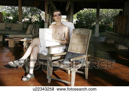 View of a man sitting with a laptop. View Large Photo Image Stock Photo - View of a man sitting with a laptop.. Fotosearch