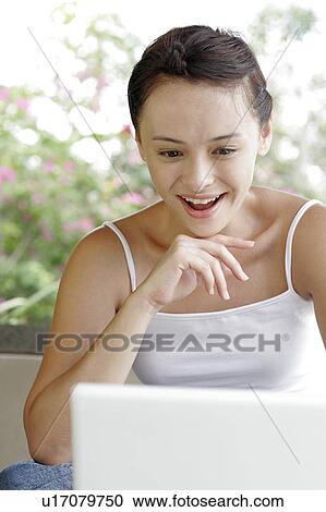 Stock Image - View of a woman sitting with a laptop.. Fotosearch