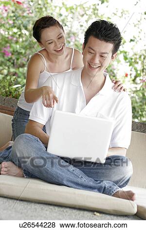 View of a young couple looking at a laptop. View Large Photo Image Stock Photo - View of a young couple looking at a laptop.. Fotosearch