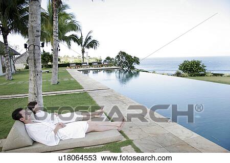 View of a young couple relaxing besides a swimming pool. View Large Photo Image Stock Image - View of a young couple relaxing besides a swimming pool.. Fotosearch