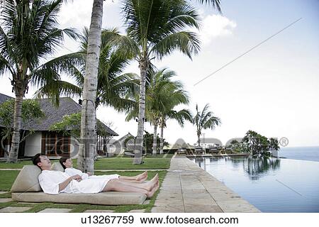View of a young couple relaxing besides a swimming pool. View Large Photo Image Stock Photo - View of a young couple relaxing besides a swimming pool.. Fotosearch