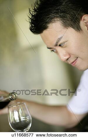 Stock Photo - View of a young man filling a glass.. Fotosearch