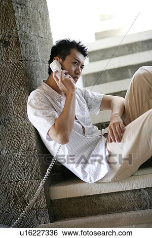 View of a young man talking on the phone. View Large Photo Image Stock Photograph - View of a young man talking on the phone.. Fotosearch