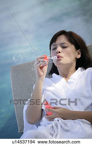 Picture - View of a young woman blowing bubbles.. Fotosearch