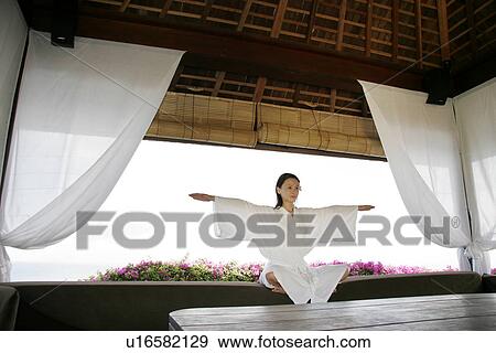 Stock Photo - View of a young woman performing yoga in a room.. Fotosearch