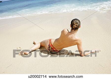Rear view of a topless woman lying on a beach. View Large Photo Image Picture - Rear view of a topless woman lying on a beach.. Fotosearch