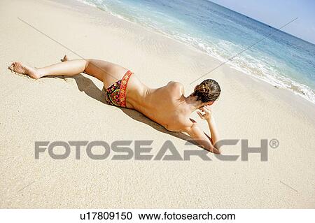 Rear view of a topless woman lying on a beach. View Large Photo Image Stock Image - Rear view of a topless woman lying on a beach.. Fotosearch