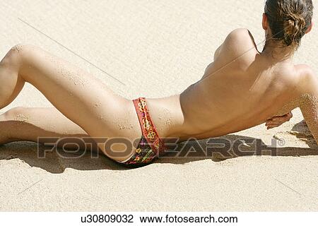 Rear view of a topless woman lying on a beach. View Large Photo Image Stock Image - Rear view of a topless woman lying on a beach.. Fotosearch