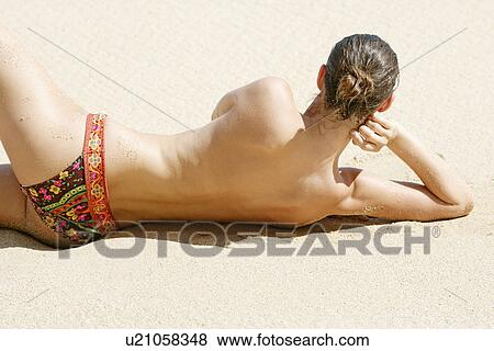 Rear view of a topless woman lying on a beach. View Large Photo Image Stock Photo - Rear view of a topless woman lying on a beach.. Fotosearch