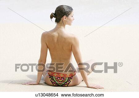Picture - Rear view of a woman exercising on a beach.. Fotosearch