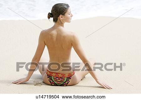 Rear view of a woman exercising on a beach. View Large Photo Image Picture - Rear view of a woman exercising on a beach.. Fotosearch
