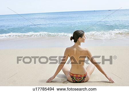 Rear view of a woman exercising on a beach. View Large Photo Image Picture - Rear view of a woman exercising on a beach.. Fotosearch