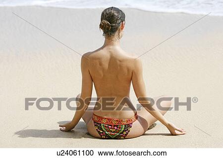 Stock Image - Rear view of a woman exercising on a beach.. Fotosearch