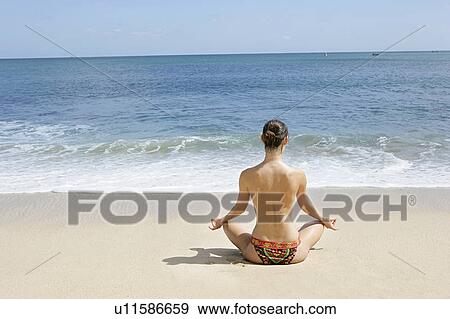 Stock Photo - Rear view of a woman exercising on a beach.. Fotosearch