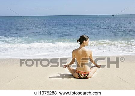 Stock Photo - Rear view of a woman exercising on a beach.. Fotosearch