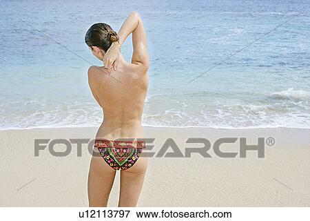 Stock Photo - Rear view of a woman exercising on a beach.. Fotosearch