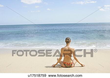 Stock Photo - Rear view of a woman exercising on a beach.. Fotosearch