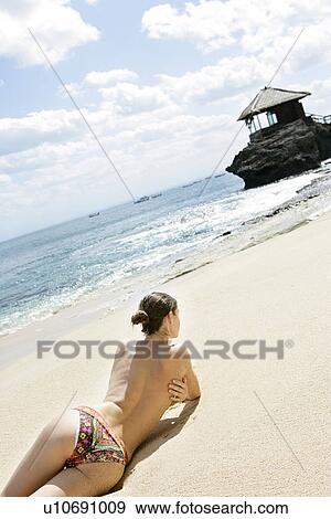 Rear view of a woman lying on a beach. View Large Photo Image Stock Photo - Rear view of a woman lying on a beach.. Fotosearch