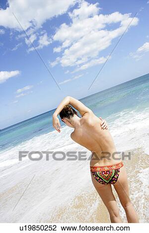 Rear view of a woman standing on a beach. View Large Photo Image Stock Image - Rear view of a woman standing on a beach.. Fotosearch
