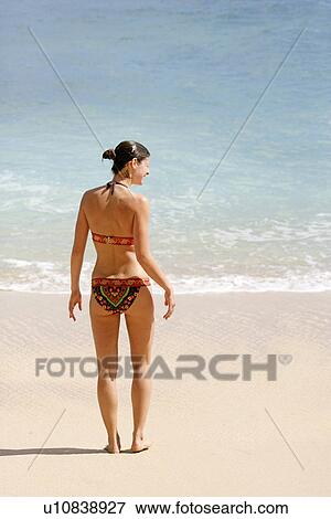 Stock Photo - Rear view of a woman standing on a beach.. Fotosearch