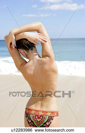Rear view of a woman standing on a beach. View Large Photo Image Stock Photograph - Rear view of a woman standing on a beach.. Fotosearch