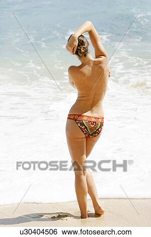 Rear view of a woman standing on a beach. View Large Photo Image Stock Photograph - Rear view of a woman standing on a beach.. Fotosearch