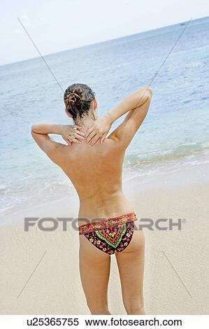 Stock Photography - Rear view of a woman standing on a beach.. Fotosearch