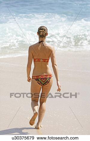 Rear view of a woman walking on a beach. View Large Photo Image Stock Photo - Rear view of a woman walking on a beach.. Fotosearch