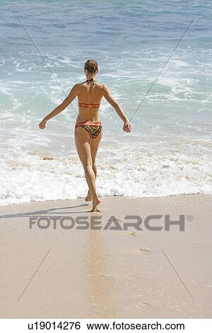 Rear view of a woman walking on a beach. View Large Photo Image Stock Photograph - Rear view of a woman walking on a beach.. Fotosearch
