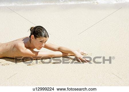 Picture - View of a topless woman lying on a beach.. Fotosearch