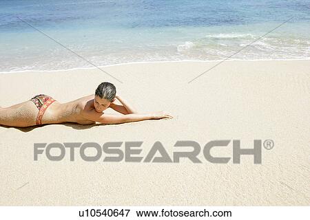 View of a topless woman lying on a beach. View Large Photo Image Stock Photo - View of a topless woman lying on a beach.. Fotosearch